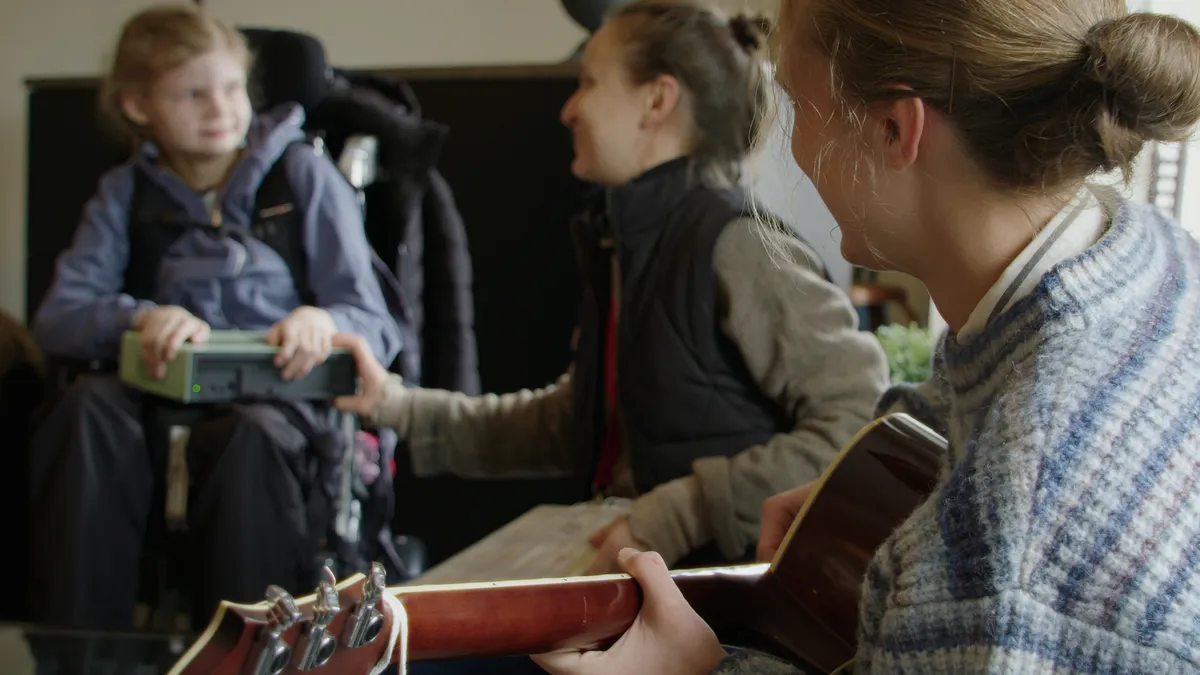Barn med Funki-instrument medan en person spelar gitarr